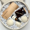 Cotton round rope basket filled with Laundry powder packaged in a paper tube, Wool dryer balls, soy candle in square amber glass and an amber glass of stain removing spray.