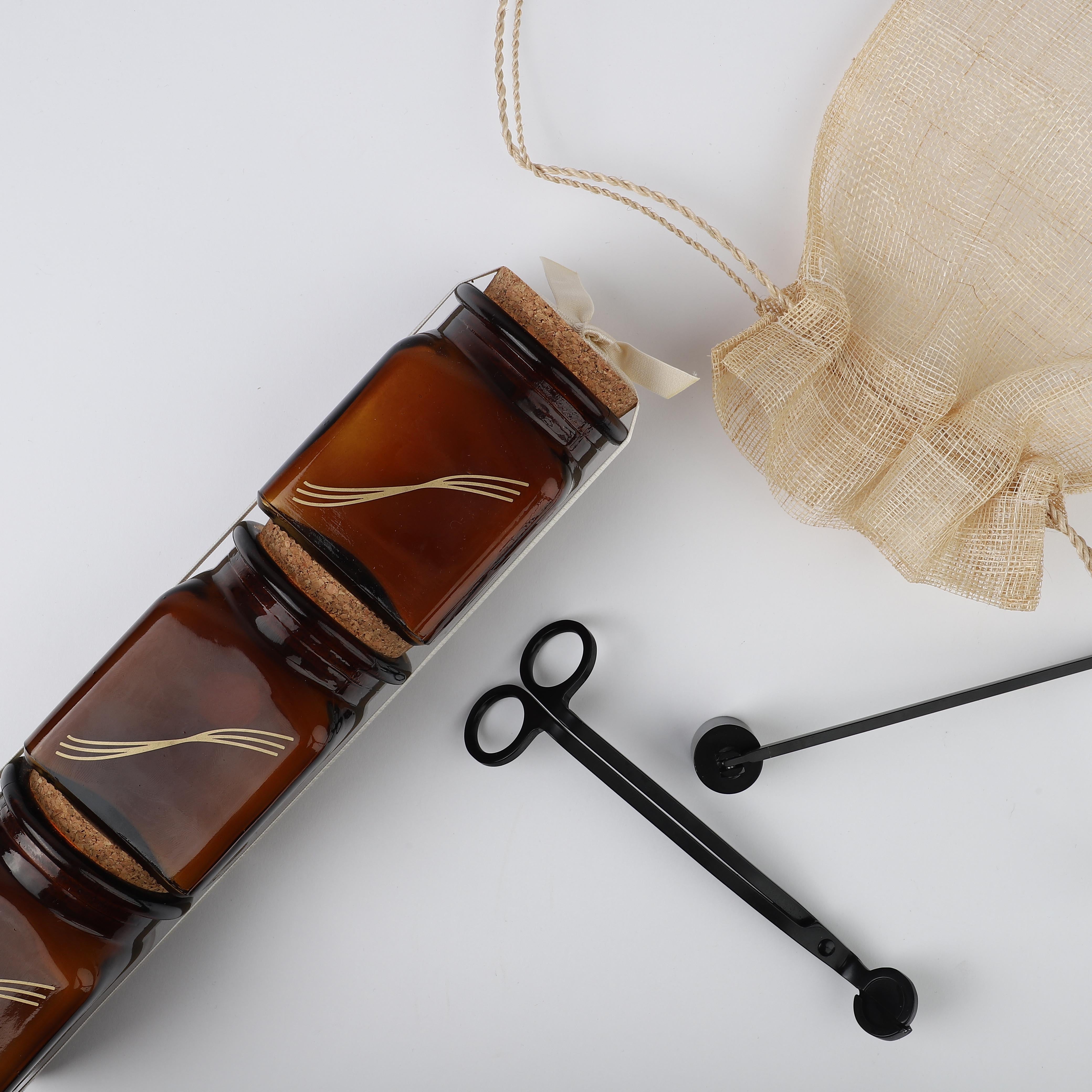 3 of Herban Body Care's ambiance soy candles in small glass amber jars with cork stoppers