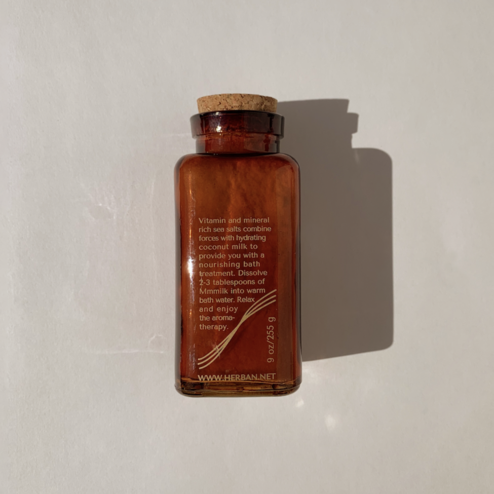 A blend of hydrating coconut milk powder, therapeutic salts, and handpicked botanical oils in glass amber jar with cork stopper