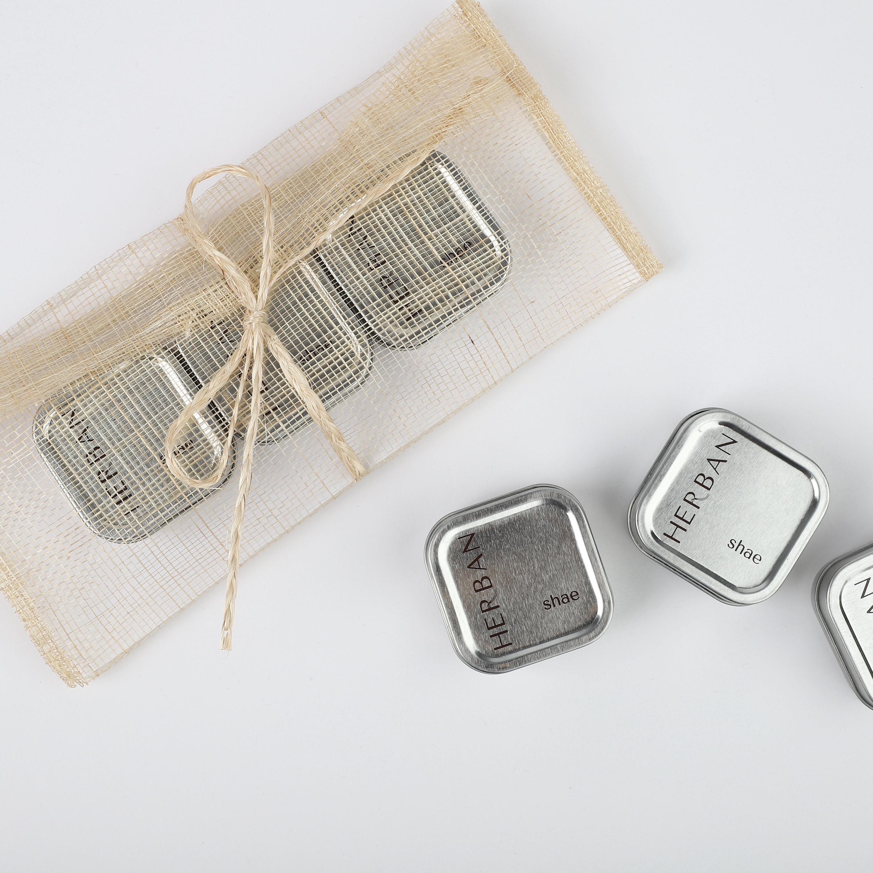 Non- greasy shae butters in an Herban small tin case, stored in  Herban's Beauty Clutch made of abaca plant fiber