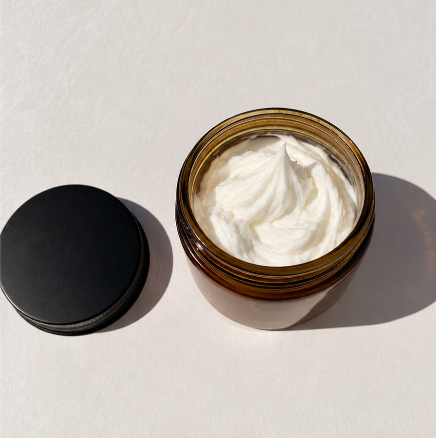 Open amber jar of Whip'd Cream showing the white whipped moisturizer, black lid beside it