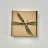 Flat kraft tuck top box closed and tied with a green linen ribbon