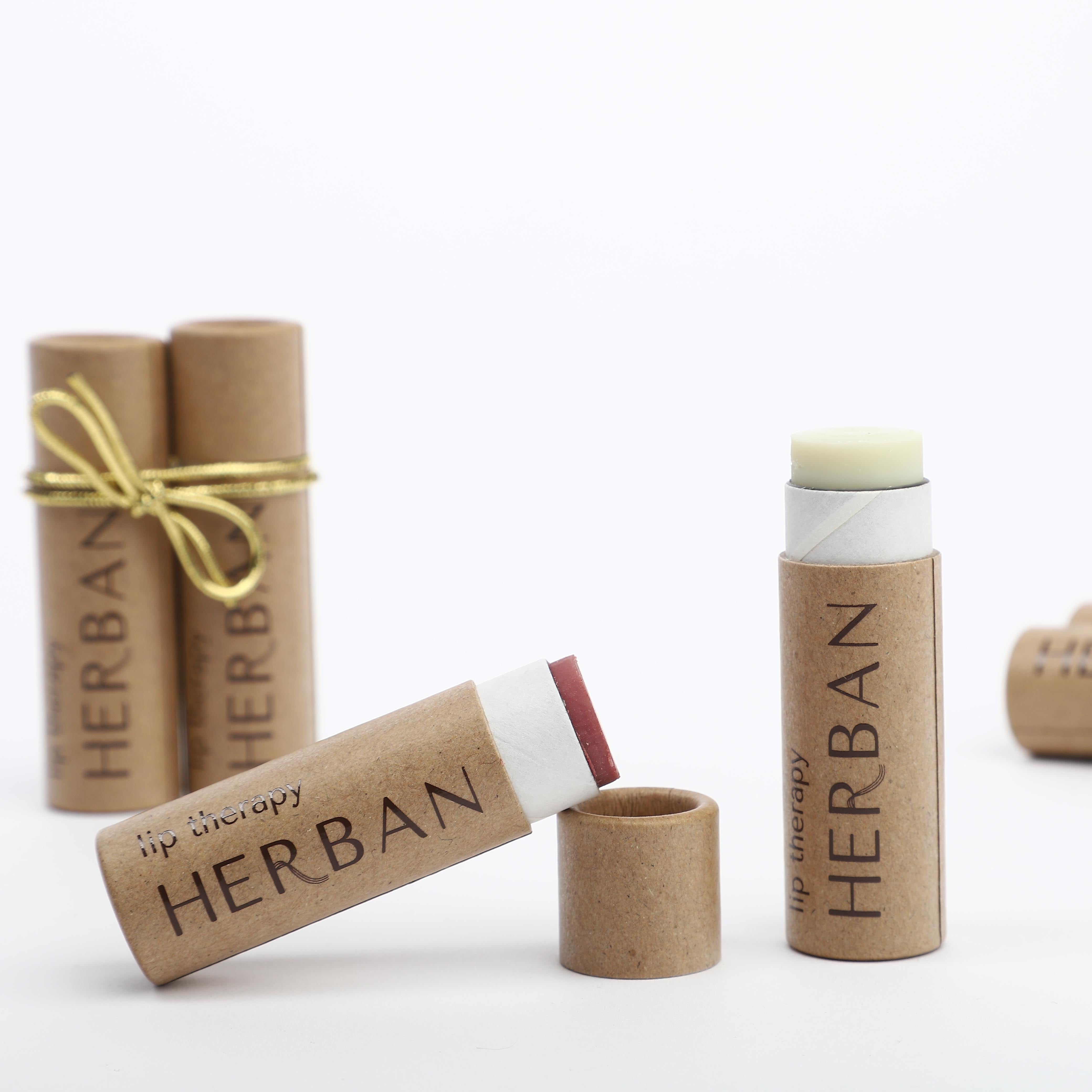 Showcasing a small collection of different varietes of Lip Therapy Lip balm made with shea butter & avocado oil and stored in plastic free, compostable packaging, complete with a small ribbon